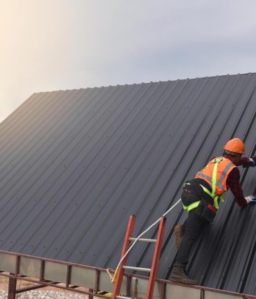 roofer-worker-use-the-ladder-in-protective-uniform-wear-and-gloves-roofing-tools-installing-new-roofs-under-construction-electric-drill-used-on-new-roofs-with-metal-sheet-free-photo
